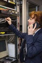 Pretty computer technician talking on phone while fixing server