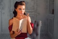 Pretty coquettish pin-up girl reads a book in retro interior