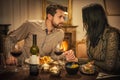 Pretty couple drinking red wine and eating in restaurant, winter time, romantic dinner Royalty Free Stock Photo