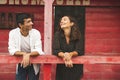 Pretty Couple Flirting and Smiling Each Other Outside of a Red Wooden Saloon