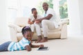 Pretty couple sitting on couch and their daughter using digital tablet Royalty Free Stock Photo