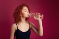 Pretty healthy young woman drinking pure mineral bottled water on a pink background Royalty Free Stock Photo