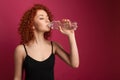 Pretty healthy young woman drinking pure mineral bottled water on a pink background Royalty Free Stock Photo