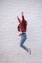 Pretty curvy girl jumping sideways next to a peculiar white wall