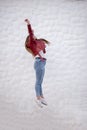 Pretty curvy girl jumping sideways next to a peculiar white wall