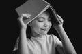 Pretty cute girl white t-shirt with copybook in the form of a roof on black background. black and white image Royalty Free Stock Photo