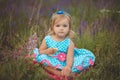 Pretty cute little girl is wearing white dress in a lavender field holding a basket full of purple flowers Royalty Free Stock Photo