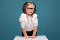 Pretty, cute little girl in white shirt, glasses, black trousers and headphones Royalty Free Stock Photo