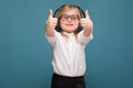 Pretty, cute little girl in white shirt, glasses, black trousers and headphones Royalty Free Stock Photo