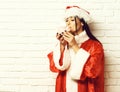 Pretty cute santa girl or brunette woman in new year sweater and christmas or xmas hat holding and kissing pink