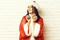 Pretty cute santa girl or smiling brunette woman in new year sweater and hat holds christmas or xmas colorful balls Royalty Free Stock Photo