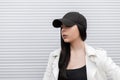Pretty cute young woman in a fashionable black baseball cap in a stylish white leather jacket in a t-shirt Royalty Free Stock Photo