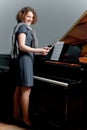 Pretty dark haired young girl standing near piano