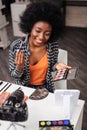 Pretty dark-skinned woman with coral lipstick holding blusher palette Royalty Free Stock Photo