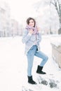Pretty darkhair girl in jeans, blue knitted sweater and uggs walks in winter city at the morning Royalty Free Stock Photo