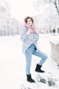 Pretty darkhair girl in jeans, blue sweater and uggs walks in winter city at the morning Royalty Free Stock Photo