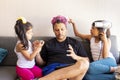 Cute daughters are painting the nails and combing the hair of their handsome young father Royalty Free Stock Photo