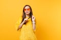 Pretty dreamy woman in fur sweater, heart orange glasses looking up thinking, dreaming holding hair isolated on bright Royalty Free Stock Photo