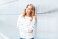 Pretty elegant positive young blond woman with a beautiful smile in a fashionable pullover near a white modern wall indoors. Royalty Free Stock Photo