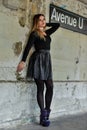 Pretty elegant young woman in black top and skirt posing over grunge wall