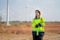 Pretty engineer woman with safety protection equipment stand with arm-crossed and look to left side stay in front of windmill