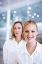 Pretty executive smiling with business woman. Portrait of pretty female executive with business woman in background.