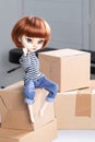 pretty expressive doll with big eyes red hairs in blue shirt hand on carton box moving crate relocation