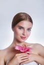 Pretty face of beautiful young woman with pink lily on hands. Concept for skin care or organic cosmetics Royalty Free Stock Photo