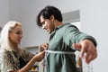 pretty fashion designer measuring smiling customer