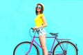 Pretty fashion smiling woman with retro pink bicycle over colorful blue