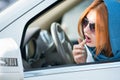 Pretty fashionable business woman driver in scarf and sunglasses checking her makeup in a mirror Royalty Free Stock Photo