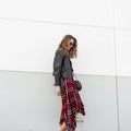 Pretty fashionable woman in red-black youth clothing from new collection in stylish sunglasses stands near vintage building on