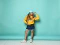 Pretty fashionable young teenager with a lovely smile posing in a baseball cap and yellow hoodie on a blue background Royalty Free Stock Photo