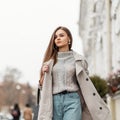 Pretty fashionable young woman walks outdoors in the city. Beautiful brown-haired girl model in stylish outerwear with a leather Royalty Free Stock Photo