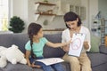 Pretty female child psychologist shows a little girl pictures with different emotions. Royalty Free Stock Photo