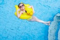 Pretty female child smiles and swims along with inflatable yellow duck-shaped circle