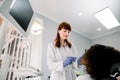 Pretty female dentist wearing gloves, performing dental check up and treatment on patients teeth. African american woman Royalty Free Stock Photo