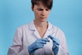 Pretty female doctor wearing white medical robe holding syringe at blue background. treatment and prevention coronavirus Royalty Free Stock Photo