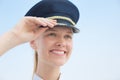 Pretty female pilot standing at the airport smiling. Aviation