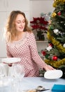 Pretty female is prepareing dishes and cutlerys for celebration of New Year Royalty Free Stock Photo