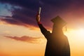 A pretty female student, celebrating her graduation and stand against the idyllic sunset view with holding her diploma Royalty Free Stock Photo