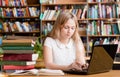 Pretty female student typing on notebook in library Royalty Free Stock Photo