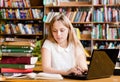 Pretty female student typing on notebook in library Royalty Free Stock Photo