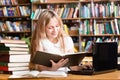 Pretty female student typing on notebook in library Royalty Free Stock Photo