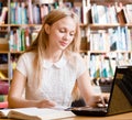 Pretty female student typing on notebook in library Royalty Free Stock Photo