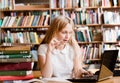 Pretty female student using laptop in library Royalty Free Stock Photo