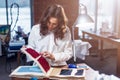 Pretty female tailor choosing a fabric in cloths catalog in studio