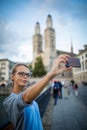 Pretty, female tourist taking selfies in front of the Grossmunster Church Royalty Free Stock Photo