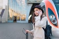 Pretty female tourist talking on the phone while standing on the platform against the background of the train.