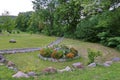 A pretty flowerbed on a green lawn with a lying stone in the middle of it and growing flowers around in a park area next Royalty Free Stock Photo